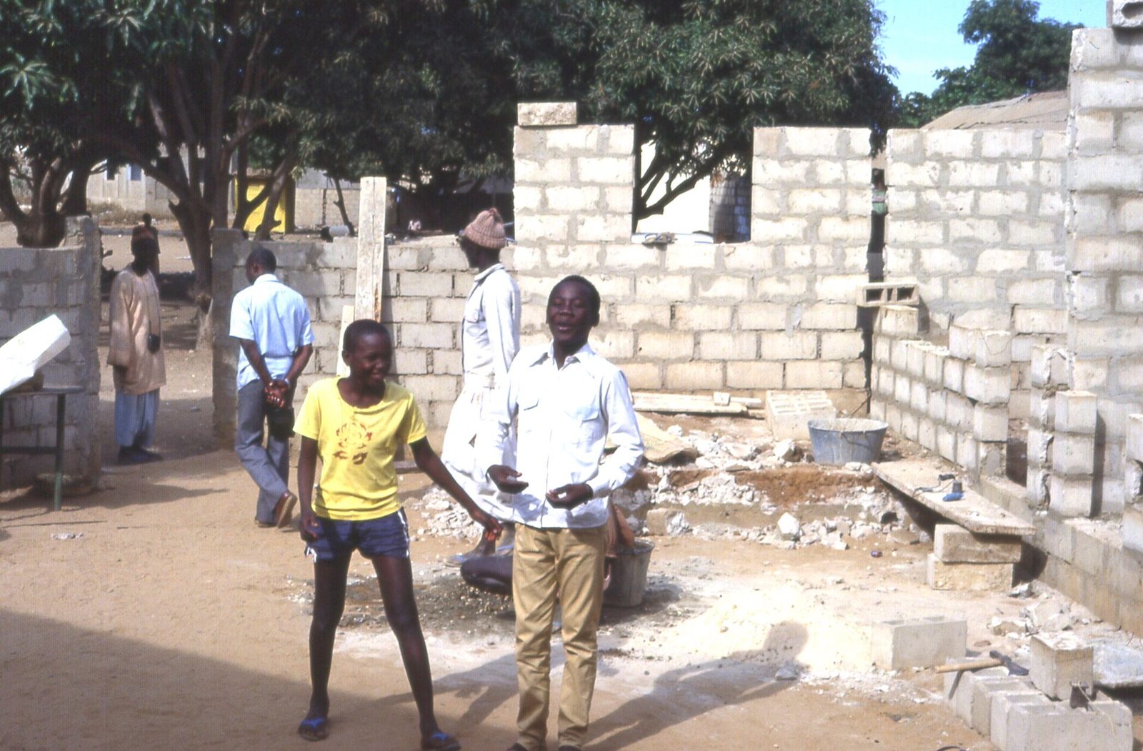 Maison en parpaings en cours de construction dans la banlieue de Dakar, avec des habitants devant le chantier