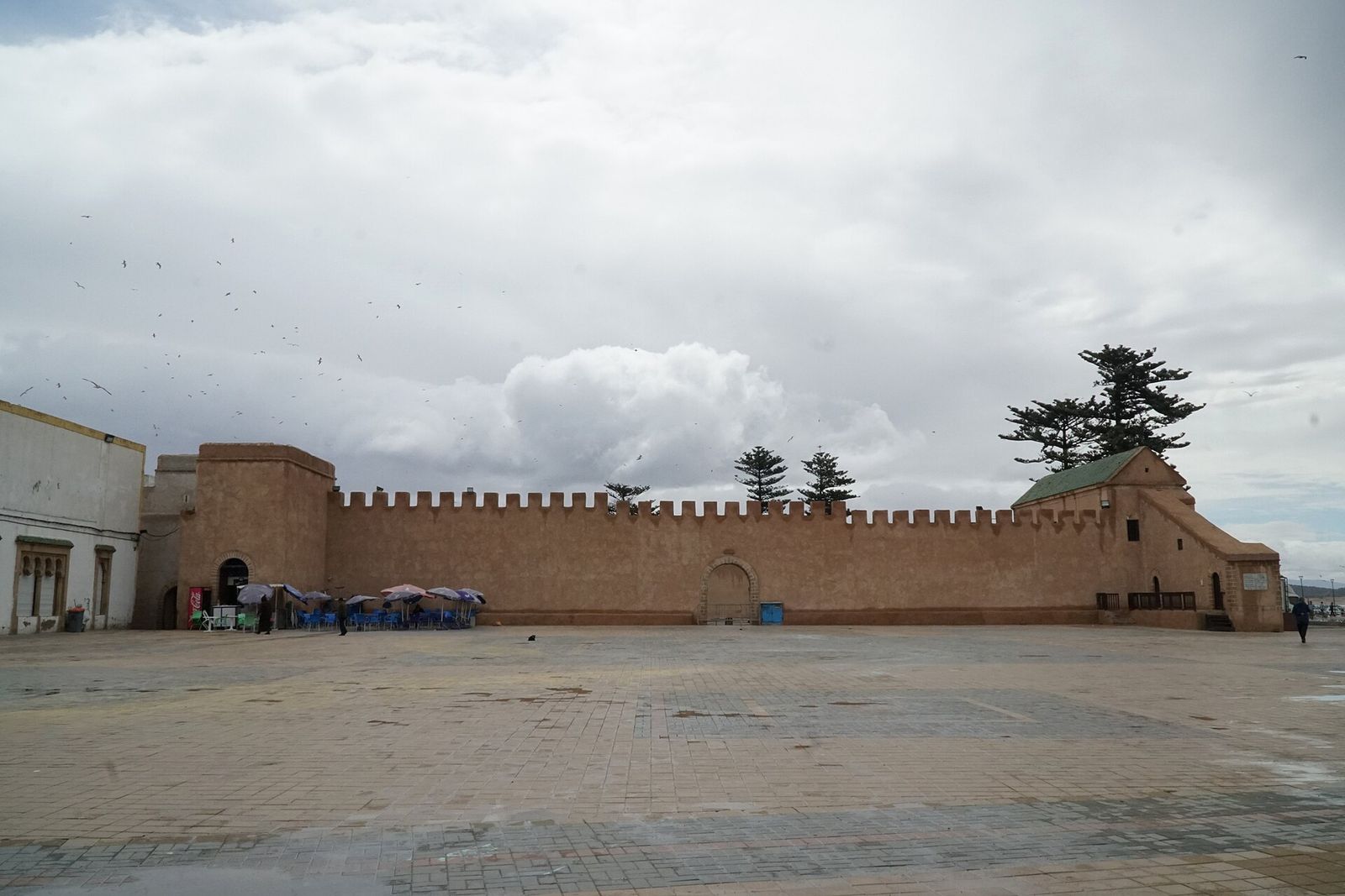 Remparts ocre de la médina d'Essaouira, au bord du port, sous un ciel nuageux