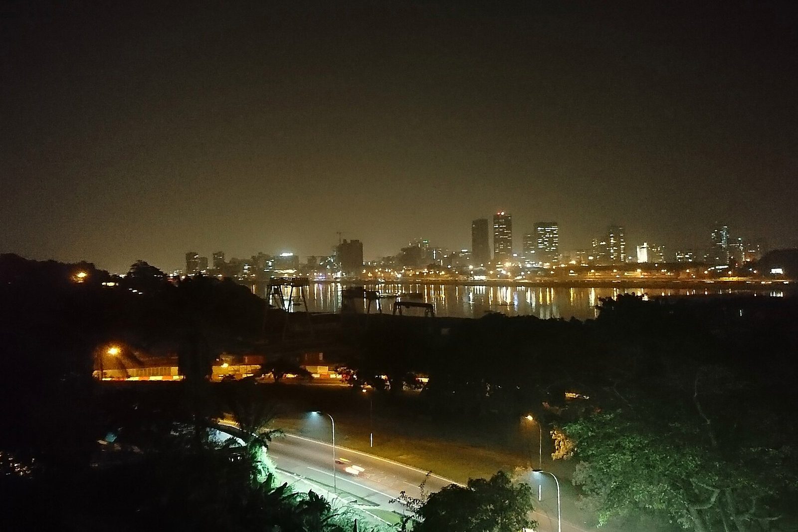 Vue nocturne du Plateau d’Abidjan et de la lagune Ébrié, avec une route éclairée au premier plan