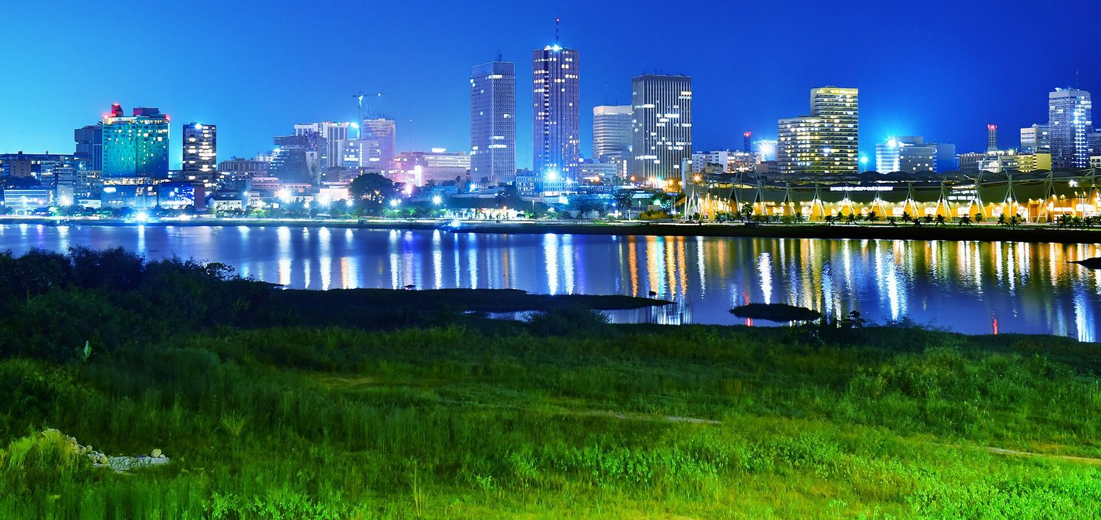 Les tours du Plateau d’Abidjan illuminées la nuit, vues depuis le pont Alassane-Ouattara au-dessus de la lagune